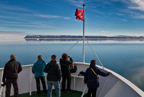 passengers admire the Arctic view from the bow of a ship in Svalbard's Hinlopen Strait
