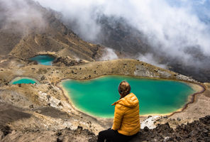 new zealand tongariro alpine crossing hiker overlooking emerald lake istk