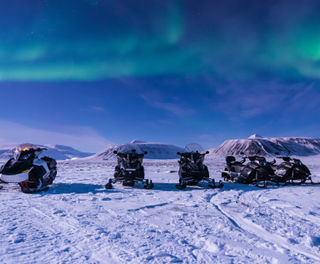 svalbard longyearbyen snowmobiles with aurora istk