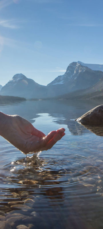 canada person scooping fresh water from crystal clear lake istk