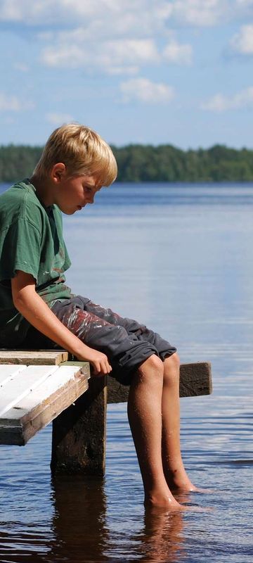 finland kids sitting on jetty by lake in summer istk