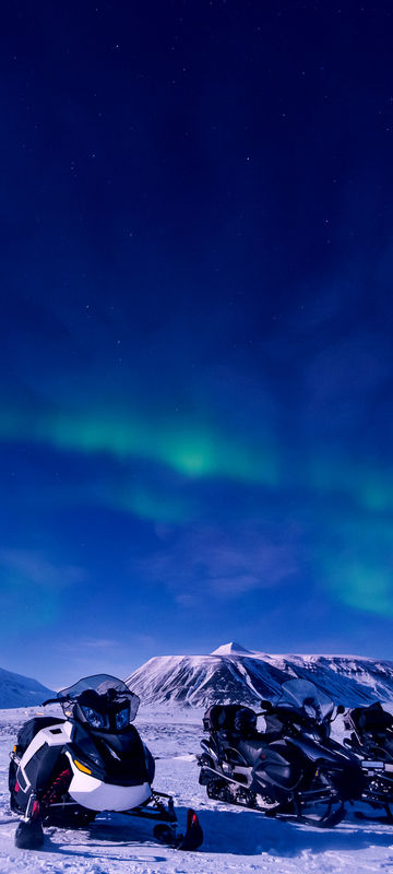 svalbard aurora over snowmobiles longyearbyen istk