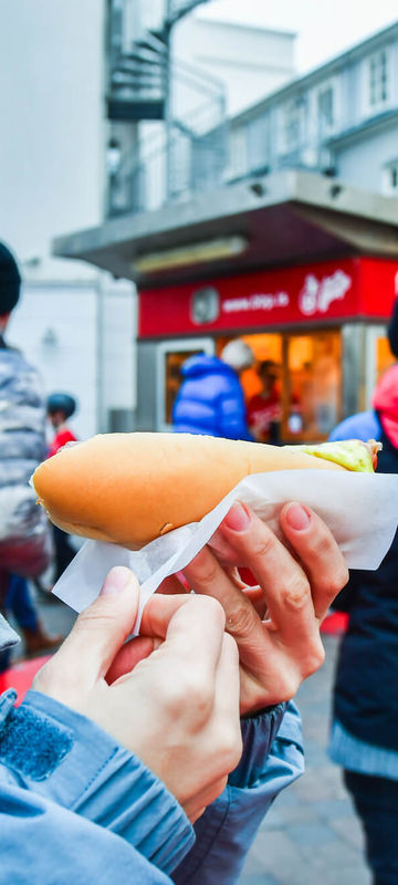 iceland-woman-tasting-famous-hot-dog-reykjavik-astk