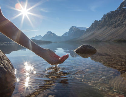 canada person scooping fresh water from crystal clear lake istk