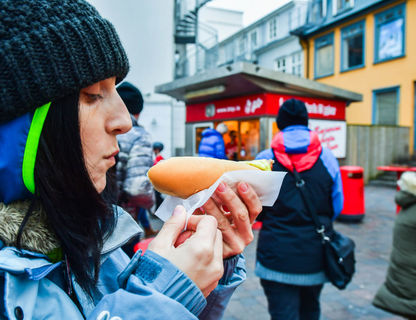 iceland-woman-tasting-famous-hot-dog-reykjavik-astk