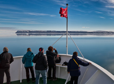 passengers admire the Arctic view from the bow of a ship in Svalbard's Hinlopen Strait