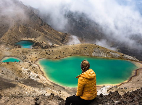 new zealand tongariro alpine crossing hiker overlooking emerald lake istk