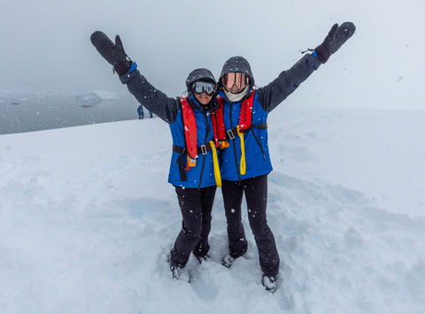 Pair of adventurers pose during a shore landing in Antarctica