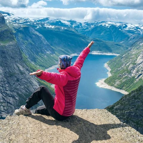 fjord norway woman sitting on edge of trolltunga istk