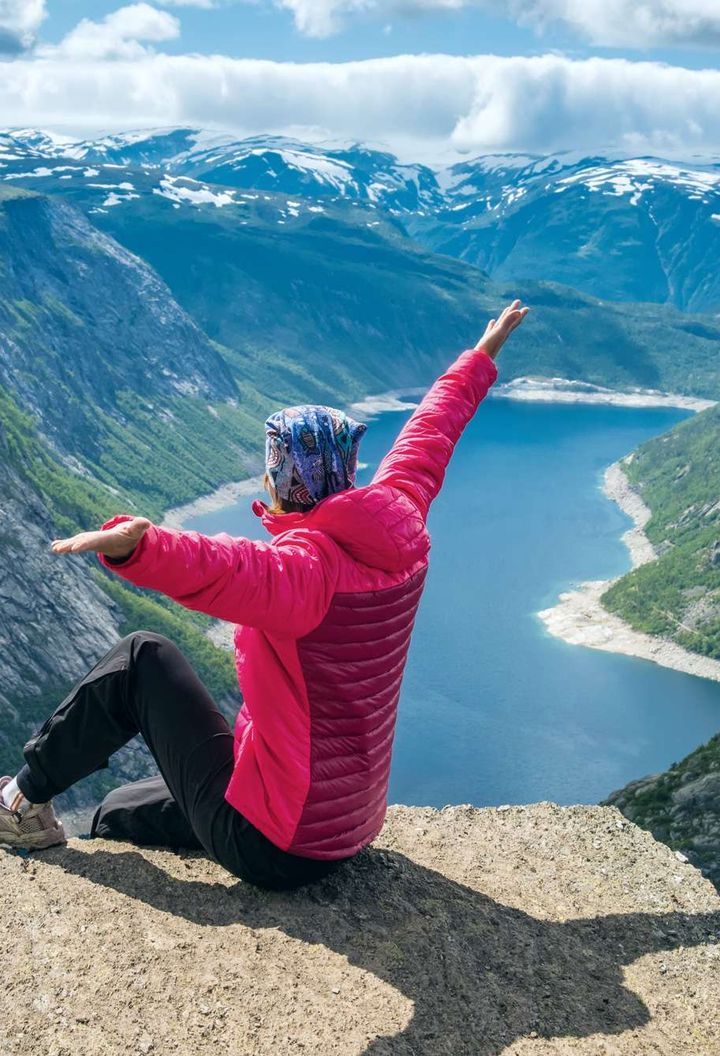 fjord norway woman sitting on edge of trolltunga istk