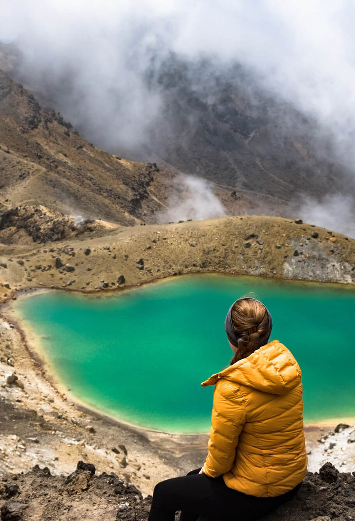 new zealand tongariro alpine crossing hiker overlooking emerald lake istk